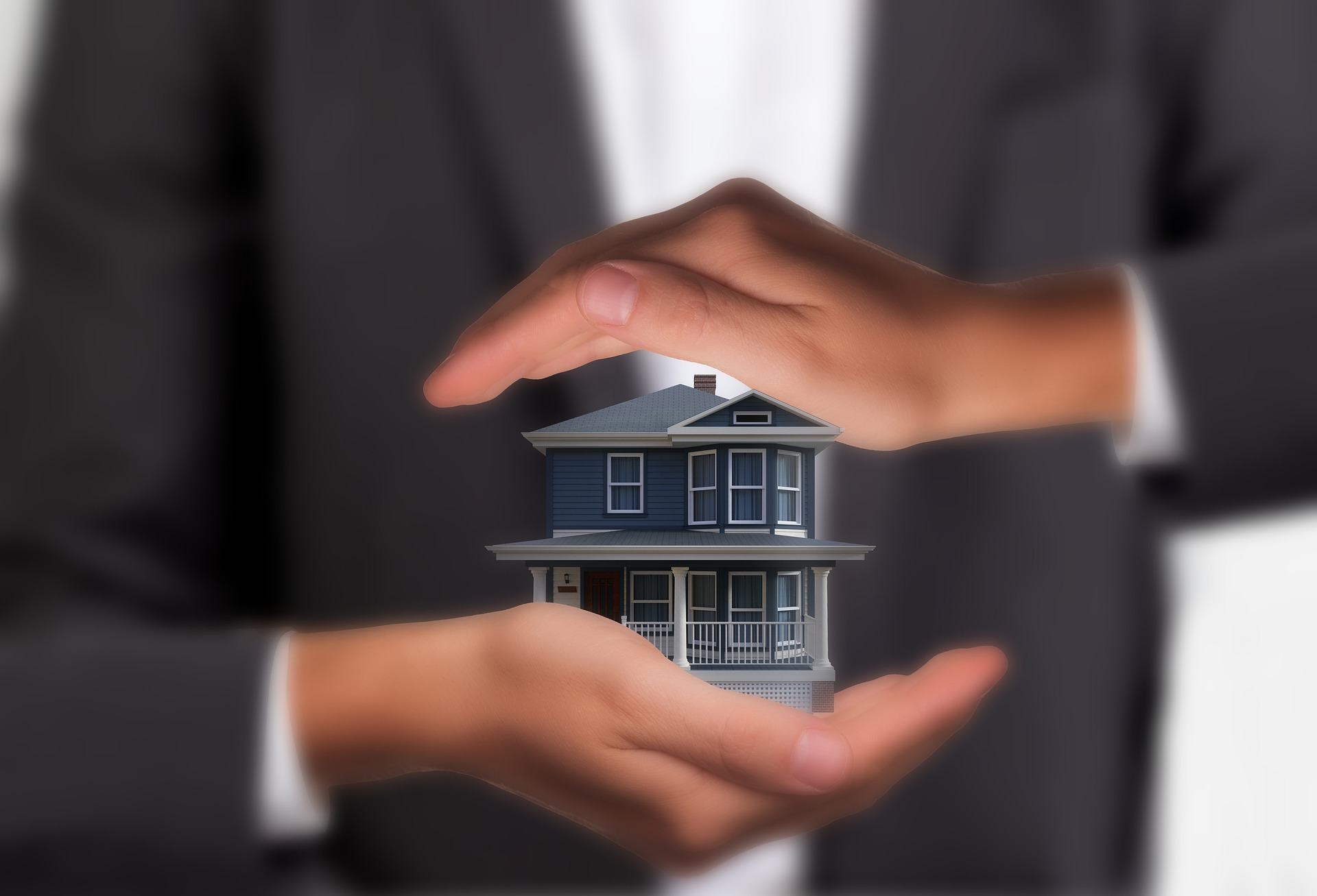 manos protegen una casa