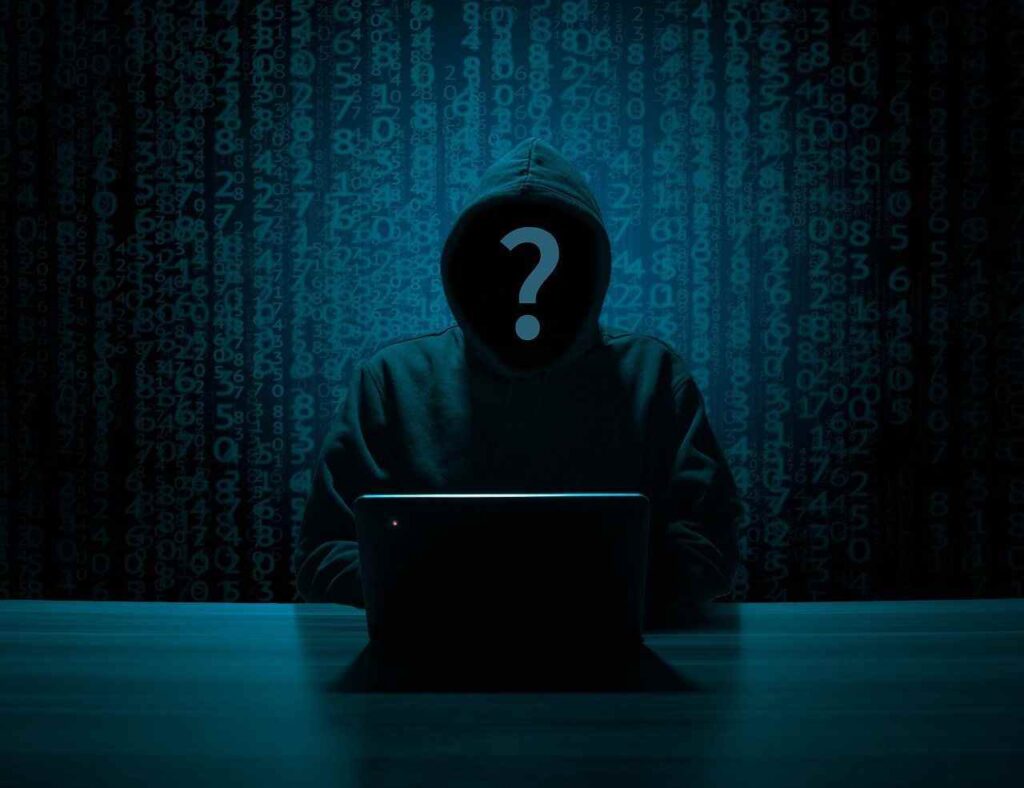 Hacker en la oscuridad con capucha y un portátil